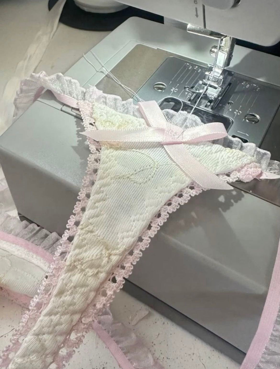 Sewing machine with a piece of fabric featuring lace trim on a white background
